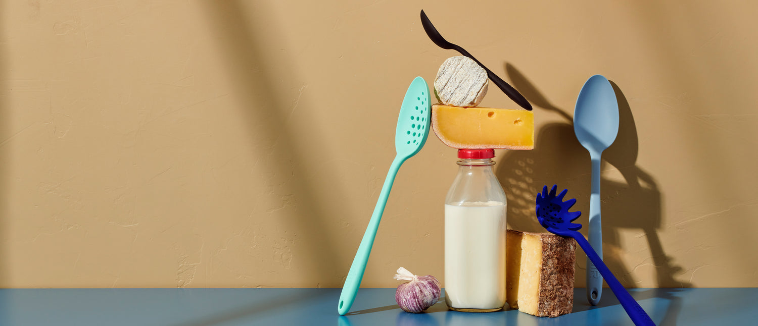 GIR tools resting on blocks of cheese and a bottle of milk on a yellowish background.