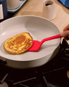 The Red Ultimate Spatula flipping a pancake. 