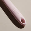 A close up of the Light Pink Spoonula handle on a cream background. 