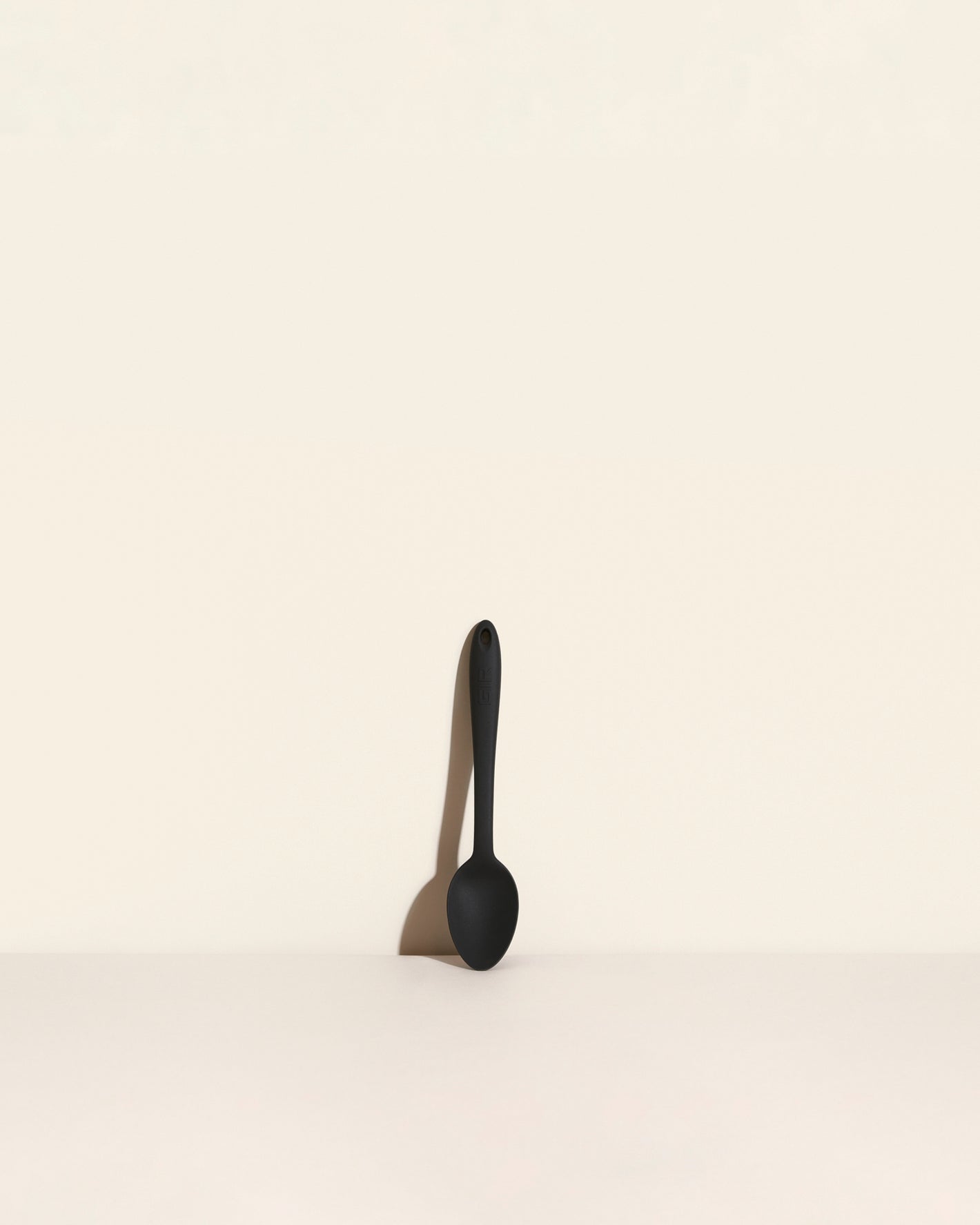 The Black Mini Spoon on a cream background. 