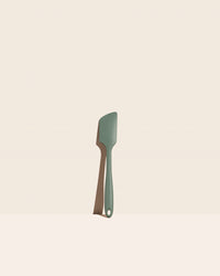 The GIR Sage Green Ultimate Spatula on a pink background.