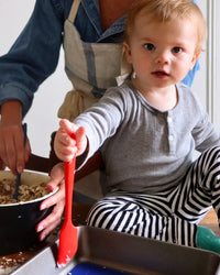 A toddler sitting beside his mom, holding the GIR mini spatula.