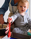 A toddler sitting beside his mom, holding the GIR mini spatula.